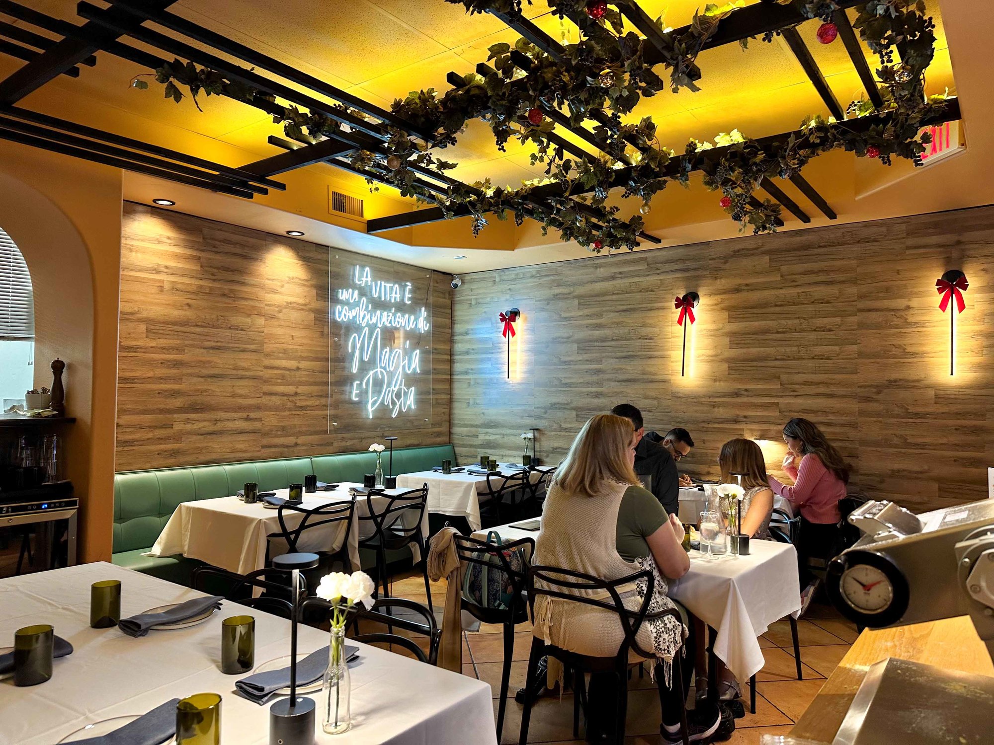 inside restaurant with tables and white linen with warm lighting and vinery on ceiling